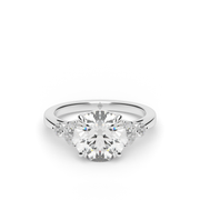 White Gold Round Shape Diamond Side Stone Engagement Ring With Shared Prong Setting.